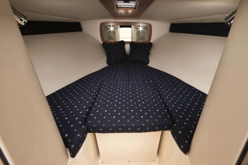 Slide: The Image of Manufacturer Provided Image: 2016 Chris-Craft Corsair 25 cabin interior with navy bedding and pillows. - 27