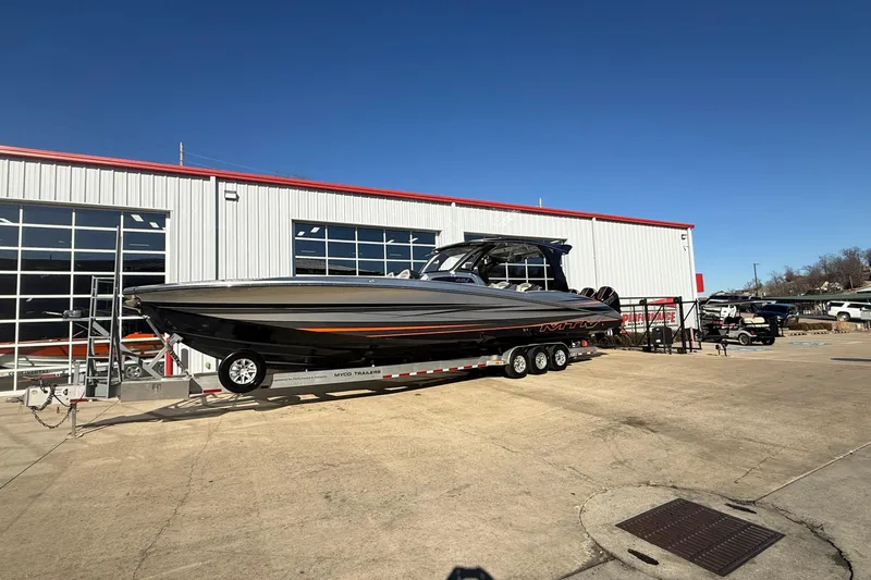 Slide: The Image of 2017 MTI 42V boat on trailer outside a garage under clear blue sky. - 3