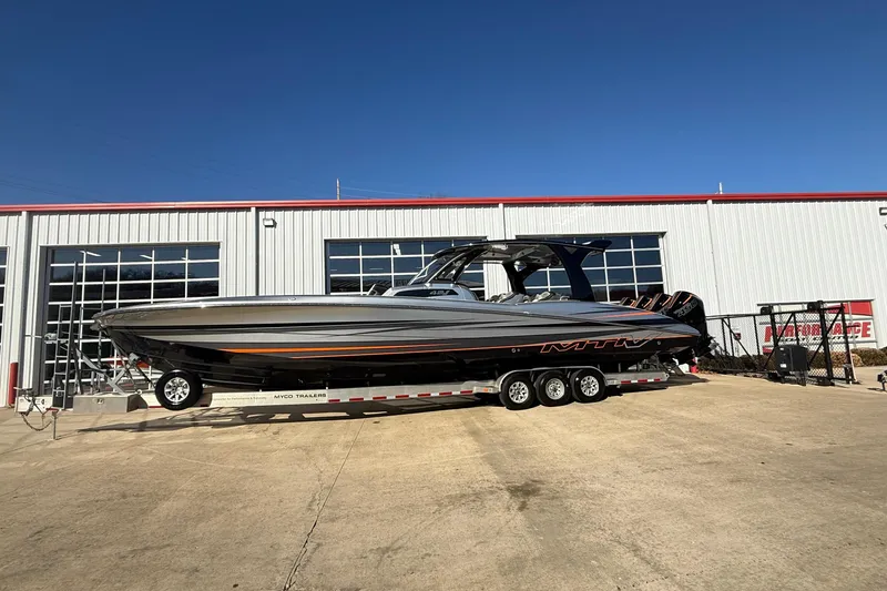 Slide: The Image of 2017 MTI 42V boat on trailer outside a large garage, clear blue sky. - 4