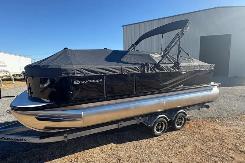 Slide: The Image of 2026 Dockside 22DQ pontoon boat with black cover on trailer, parked outdoors. - 2