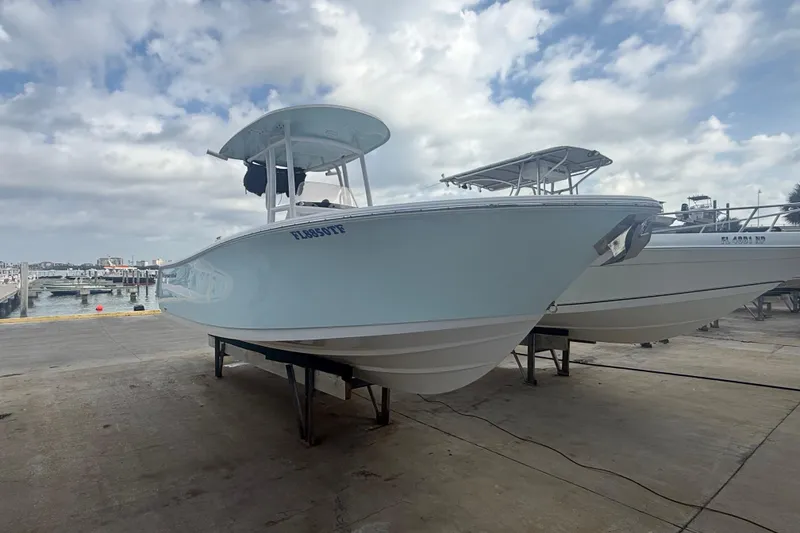 Slide: The Image of 2022 Sportsman Open 232 Center Console boat on a dock under cloudy skies. - 2