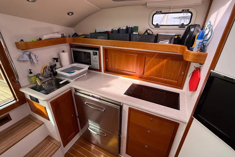 Slide: The Image of Compact kitchen in 2012 MJM 40z yacht with stove, microwave, and wooden cabinetry. - 32
