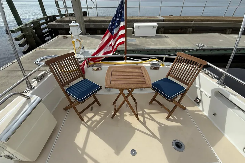 Slide: The Image of 2012 MJM 40z yacht deck with wooden chairs, table, and American flag. - 6
