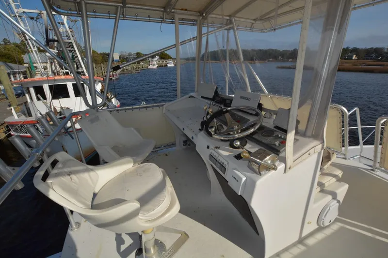 Slide: The Image of 1983 Key West #1 Sport Fish boat helm with steering wheel and controls, docked by the water. - 6