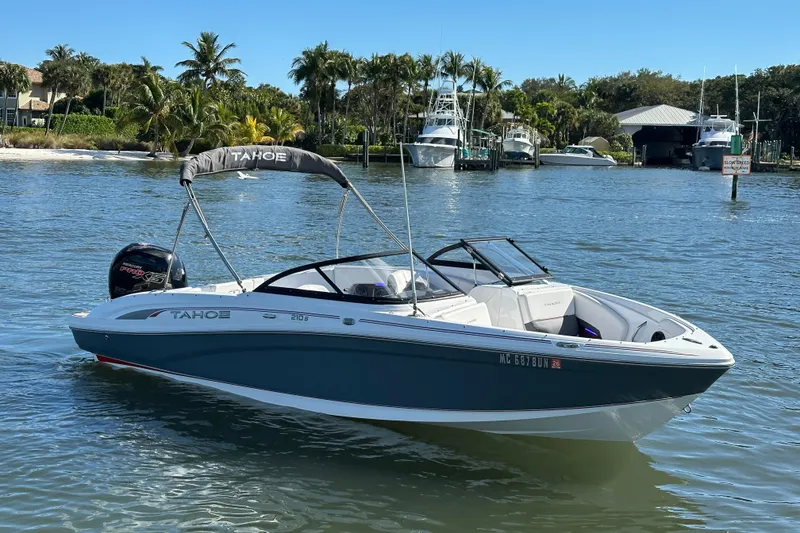 The Image of 2021 Tahoe 210 S boat on a sunny day, surrounded by palm trees and calm water. - 0