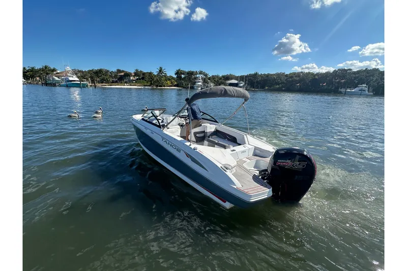 The Image of 2021 Tahoe 210 S boat on calm water under a clear blue sky. - 1