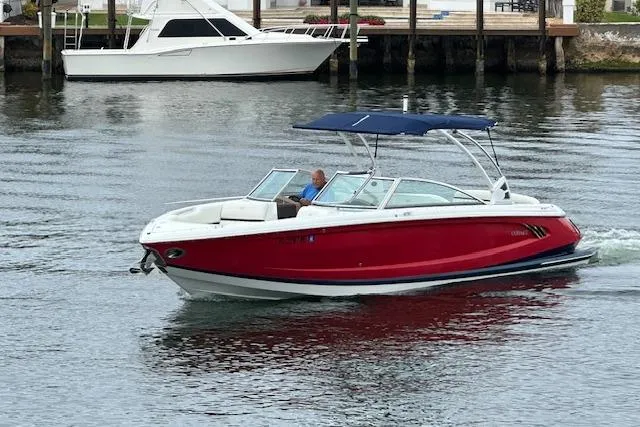 Slide: The Image of 2016 Cobalt A28 boat with red hull cruising on calm water. - 19