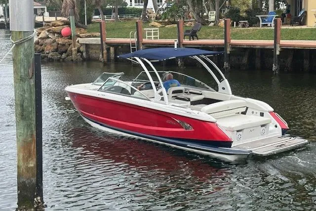 Slide: The Image of 2016 Cobalt A28 boat with red hull and blue canopy cruising in a canal. - 20