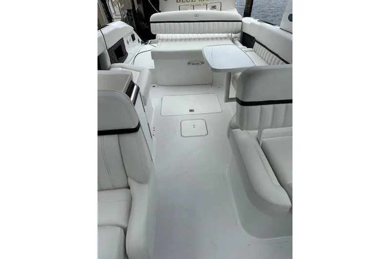 Slide: The Image of 2016 Cobalt A28 boat interior with white seating and table, docked by water. - 33