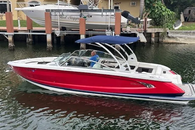 Slide: The Image of 2016 Cobalt A28 boat with red hull and blue canopy on a calm waterway. - 4