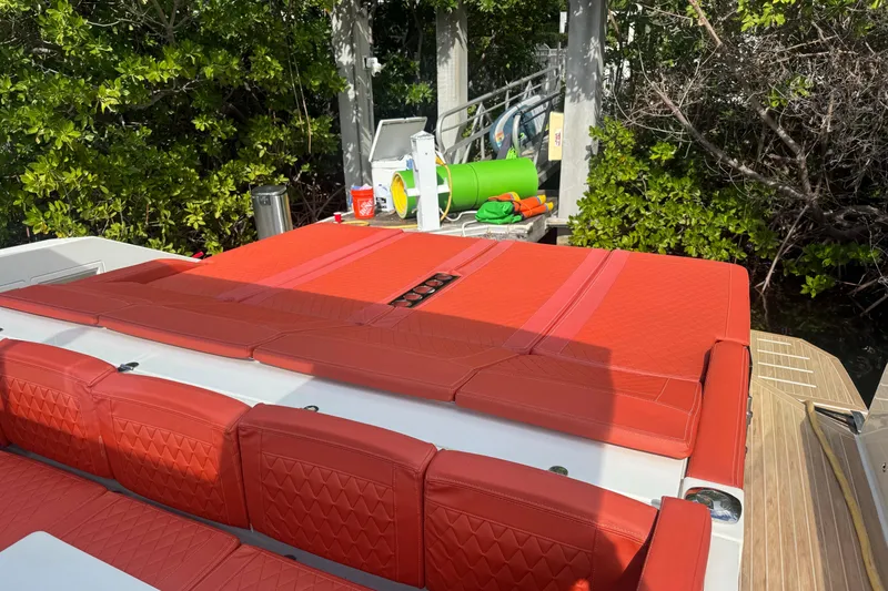 Slide: The Image of 2022 De Antonio Yachts D42 Open with vibrant red seating, docked near lush greenery. - 4