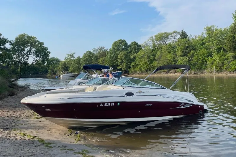 Slide: The Image of 2006 Sea Ray 240 Sundeck boat on display, red and white exterior, docked outdoors. - 2