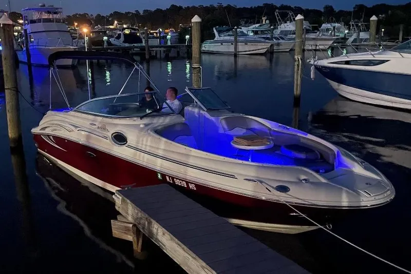 Slide: The Image of 2006 Sea Ray 240 Sundeck boat docked at night with blue interior lighting. - 3