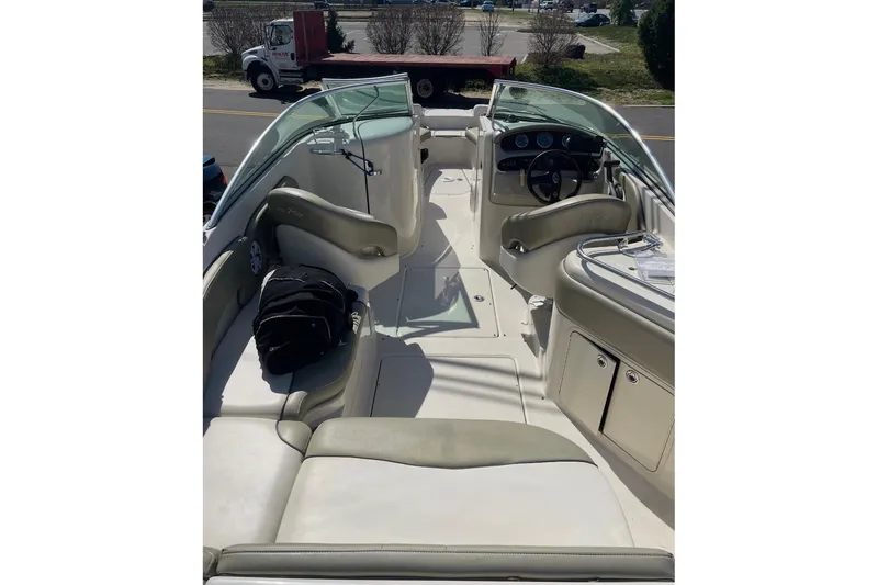 Slide: The Image of 2006 Sea Ray 240 Sundeck interior with seating and helm, parked near a road. - 6