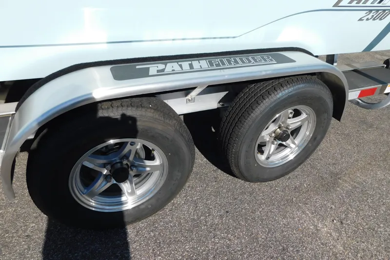 Slide: The Image of Trailer wheels of a 2026 Pathfinder 2300 HPS boat on pavement. - 24