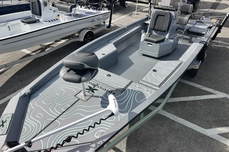 Slide: The Image of 2026 Xpress H24B Bay boat with modern seating and sleek design in a parking lot. - 8