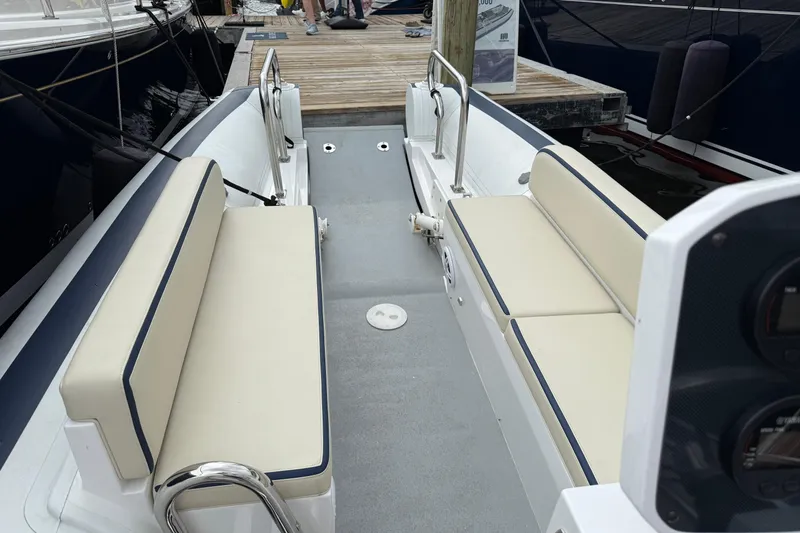 Slide: The Image of 2024 Novurania Catamaran 20 interior with beige seating and dock view. - 10