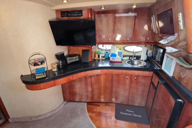Slide: The Image of Interior of 2002 Regal Commodore 4260 yacht with kitchenette, TV, and wooden cabinetry. - 49