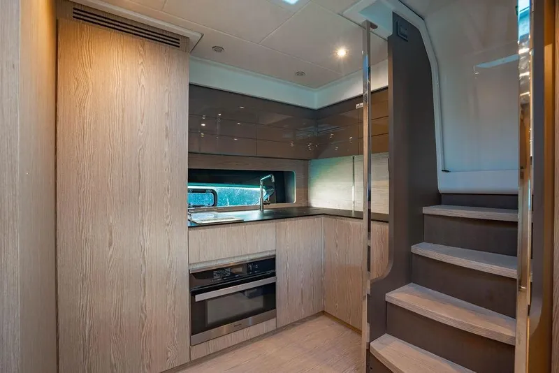 Slide: The Image of Modern kitchen interior of 2022 Azimut Atlantis 45 yacht, featuring sleek wood cabinetry and stairs. - 6