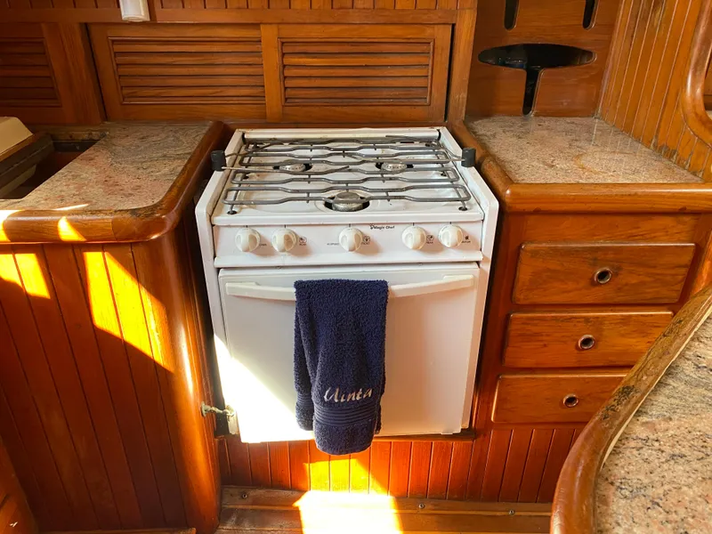 Slide: The Image of 1981 Hans Christian 38 Mark II yacht kitchen with stove, wooden cabinetry, and granite countertops. - 10