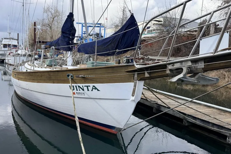 Slide: The Image of 1981 Hans Christian 38 Mark II sailboat docked, featuring wooden accents and blue covers. - 70