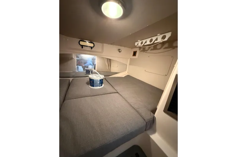 Slide: The Image of 2005 Grady-White Express 330 cabin interior with gray cushions and overhead light. - 22