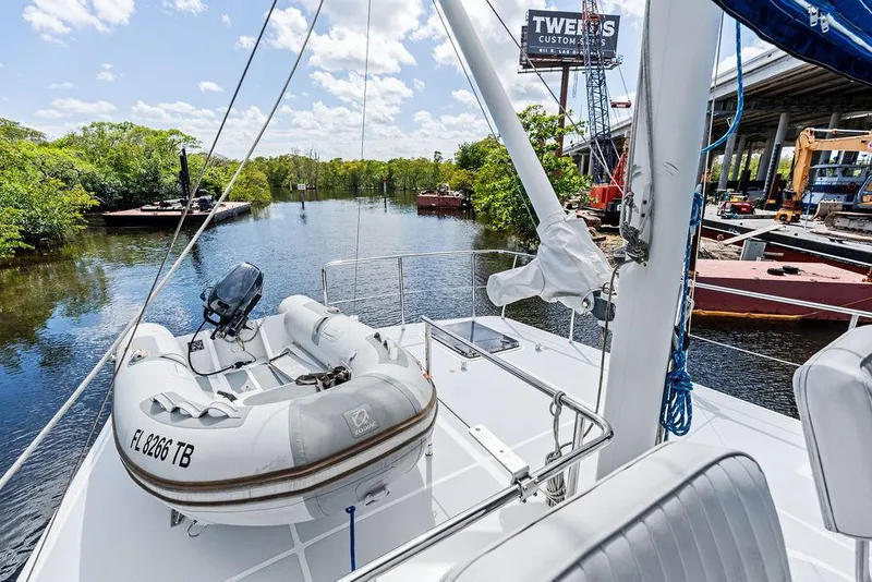 Slide: The Image of Selene Solo 2000 yacht with dinghy on deck, docked near lush riverbank and industrial area. - 10