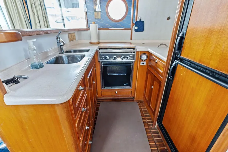 Slide: The Image of Compact kitchen in a 2000 Selene Solo boat, featuring wooden cabinetry and modern appliances. - 21
