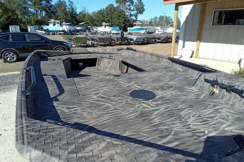 Slide: The Image of 2026 Alweld 1652 Invader boat with camo pattern, parked outdoors near other boats. - 6