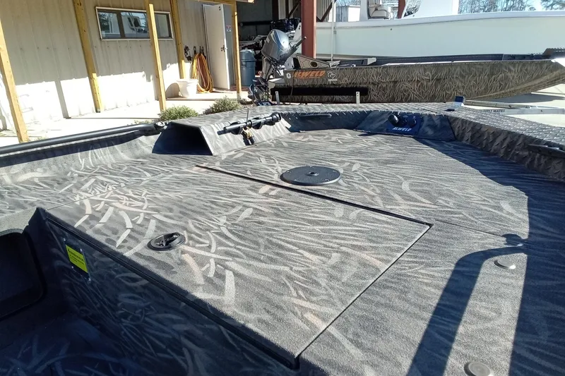 Slide: The Image of 2026 Alweld 1652 Invader boat with camo pattern, docked outdoors. - 7