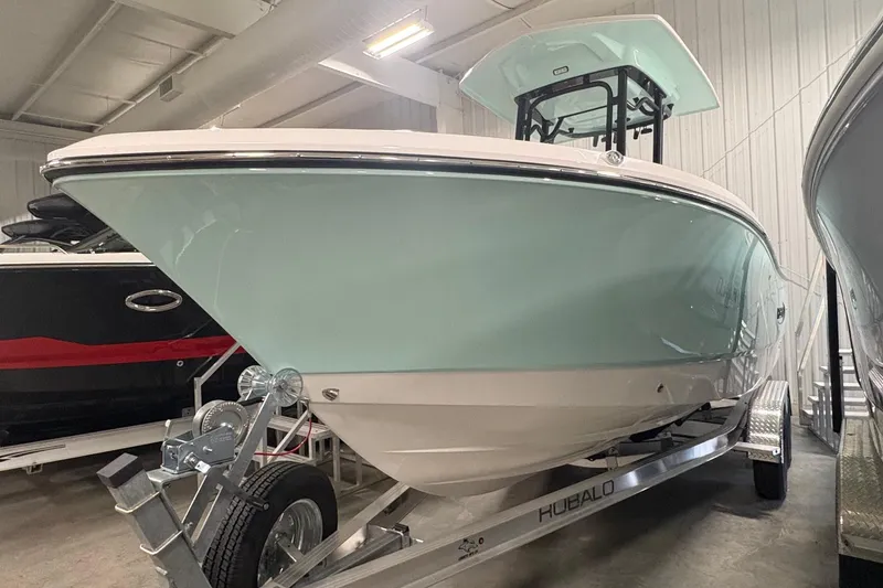 Slide: The Image of 2025 Robalo R232 Explorer boat on trailer in indoor showroom. - 2