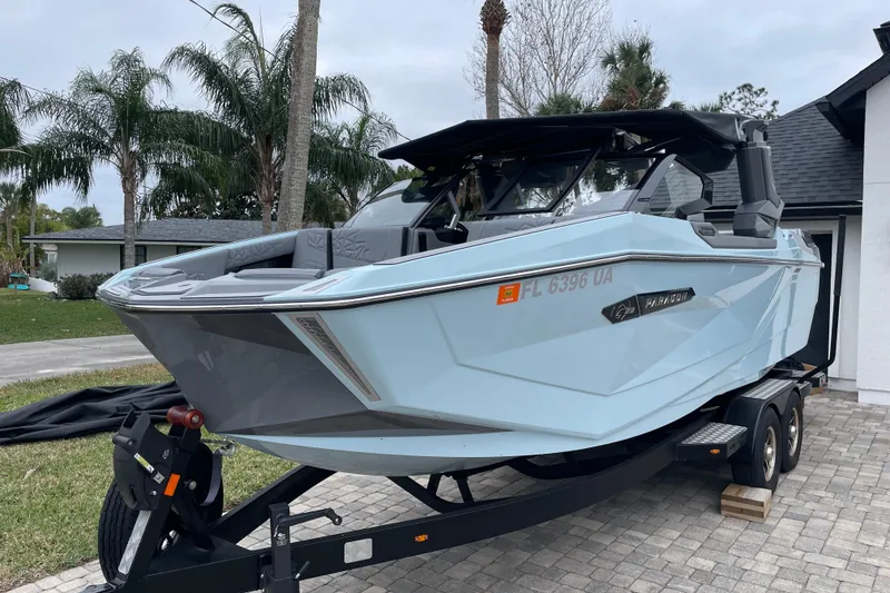 Slide: The Image of 2025 Nautique Super Air Nautique G23 Paragon boat on trailer, parked near palm trees. - 2