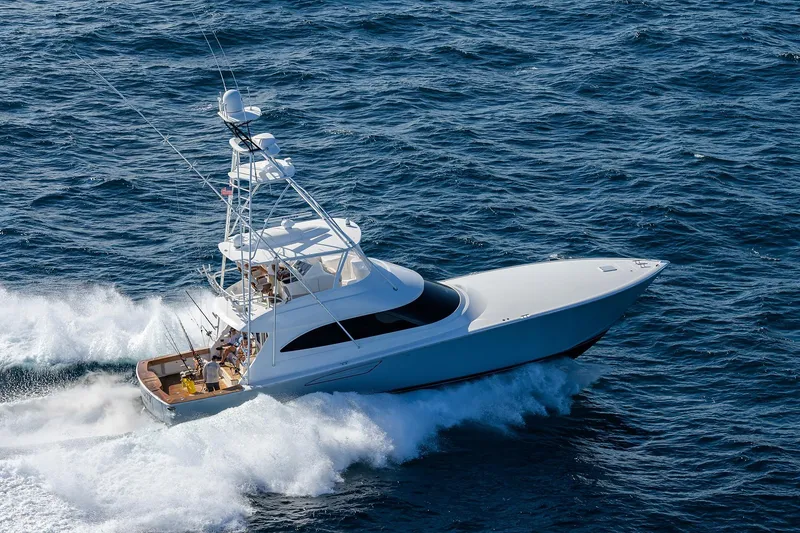Slide: The Image of 2015 Viking 62 Convertible yacht cruising near lush greenery and buildings. - 0