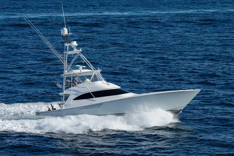 Slide: The Image of 2015 Viking 62 Convertible yacht cruising near lush green foliage. - 1