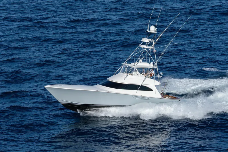 Slide: The Image of 2015 Viking 62 Convertible yacht cruising near lush green shoreline. - 2