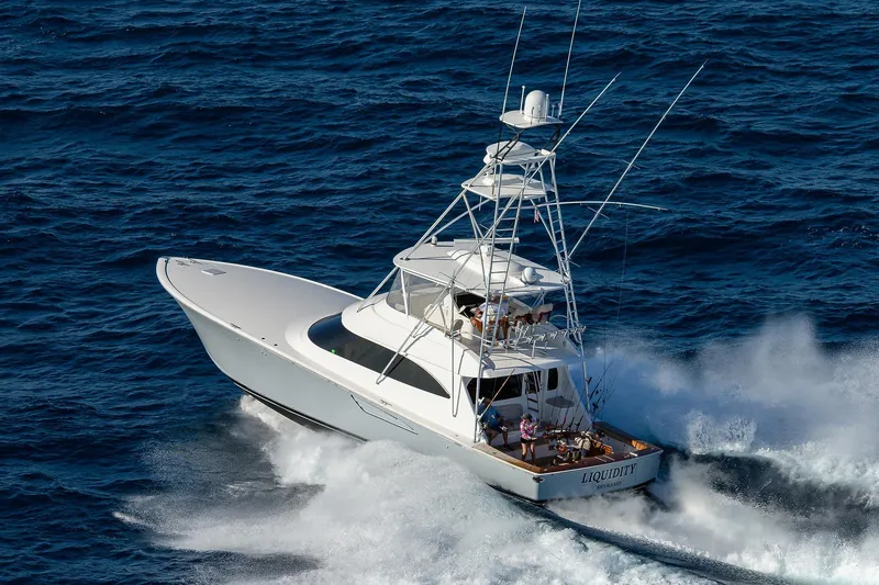 Slide: The Image of 2015 Viking 62 Convertible yacht cruising near lush green shoreline. - 3