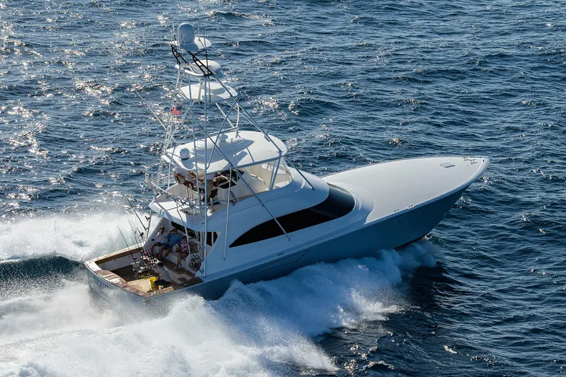 Slide: The Image of 2015 Viking 62 Convertible yacht cruising near lush green shoreline. - 4