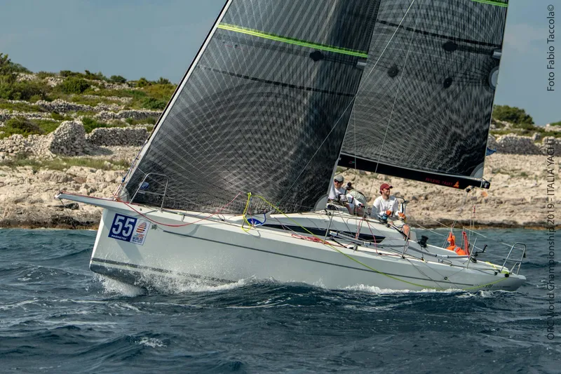 Slide: The Image of Italia Yachts 9.98 sailing near rocky coastline, 2026 model. - 3