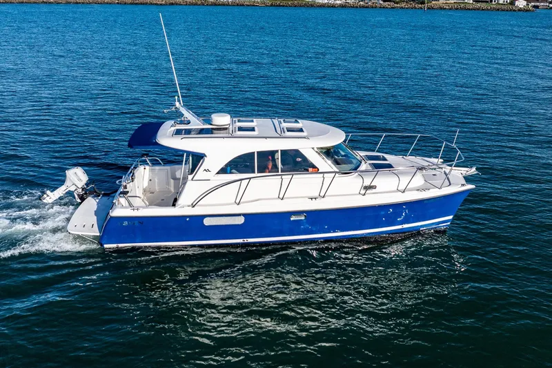 The Image of A 2012 Aspen C90 boat cruising on blue water, featuring a sleek white and blue design. - 0