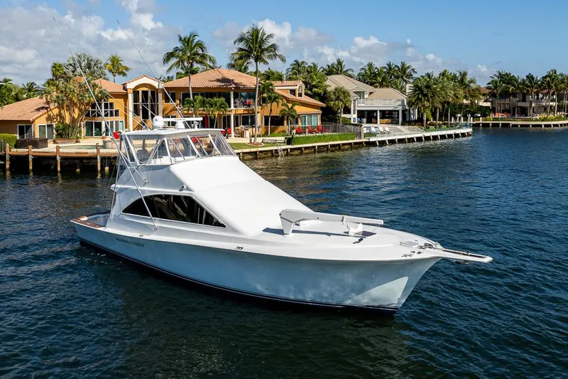 Slide: The Image of 1999 Ocean Yachts 60 Convertible cruising near waterfront homes, under a clear blue sky. - 9