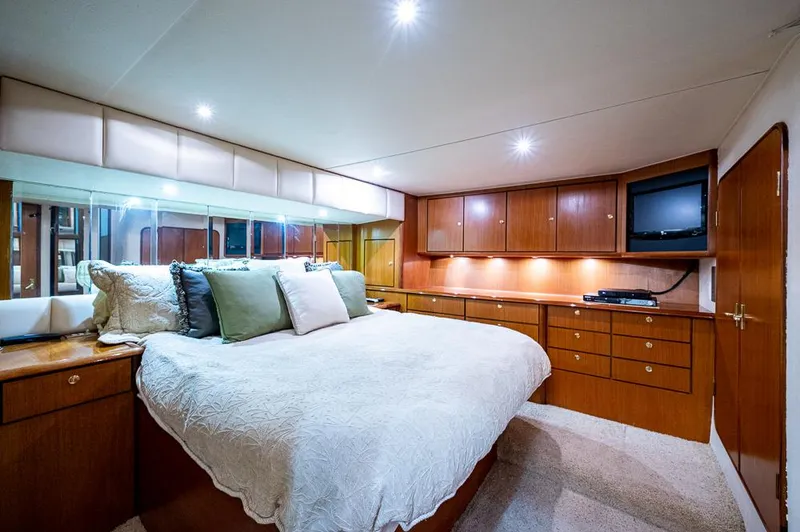 Slide: The Image of Luxurious bedroom in 1999 Ocean Yachts 60 Convertible, featuring elegant wood cabinetry and cozy lighting. - 25