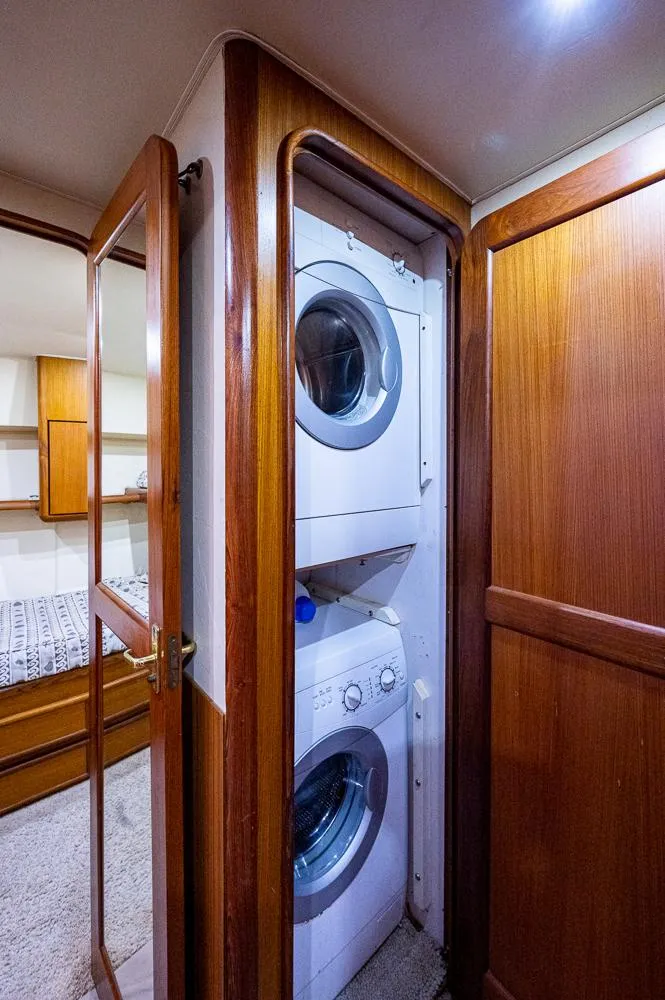 Slide: The Image of 1999 Ocean Yachts 60 Convertible interior with stacked washer and dryer in wooden cabinet. - 40