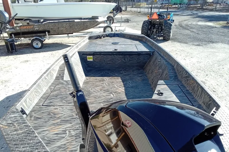 Slide: The Image of 2026 Alweld 1552 Invader boat with camo interior, parked outdoors near a tractor. - 11
