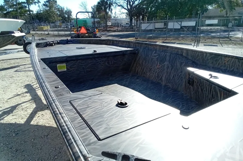 Slide: The Image of 2026 Alweld 1552 Invader boat with camo interior, parked outdoors on a sunny day. - 8