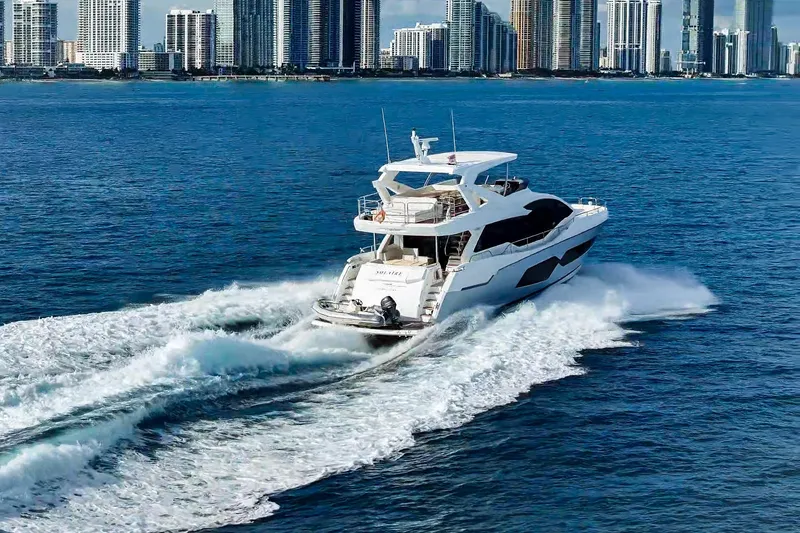 Slide: The Image of 2019 Sunseeker 76 Yacht cruising near city skyline on blue ocean waters. - 10