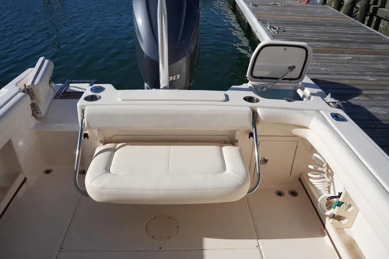 Slide: The Image of 2016 Grady-White Freedom 255 boat interior with seating and storage, docked by water. - 19