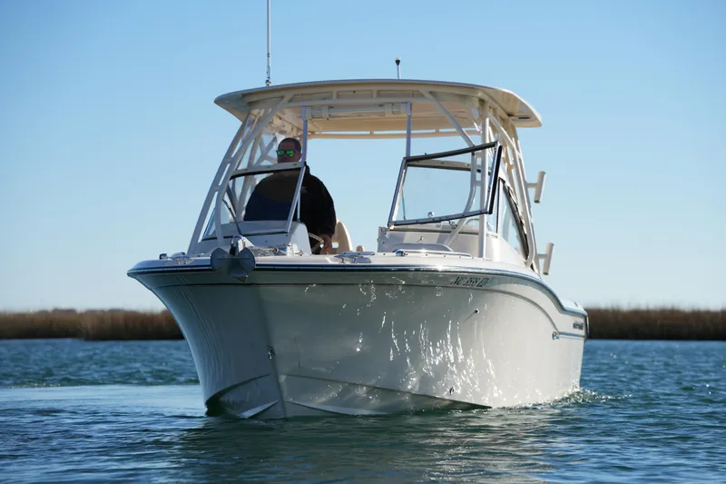 Slide: The Image of 2016 Grady-White Freedom 255 boat cruising on calm water under clear blue sky. - 2