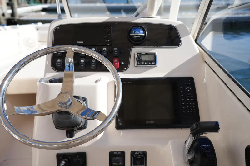 Slide: The Image of Helm of 2016 Grady-White Freedom 255 boat with steering wheel and navigation controls. - 28