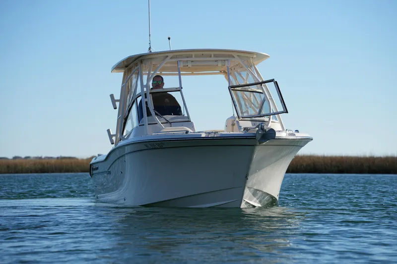 Slide: The Image of 2016 Grady-White Freedom 255 boat cruising on calm water under clear blue sky. - 4