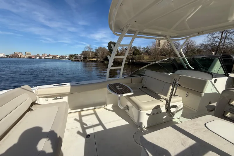 Slide: The Image of 2014 Boston Whaler 270 Vantage boat interior with seating, table, and waterfront view. - 10